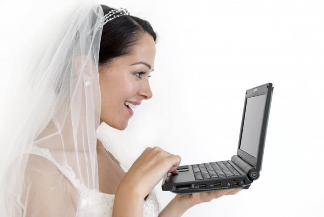a woman wearing a bridal veil holding a laptop